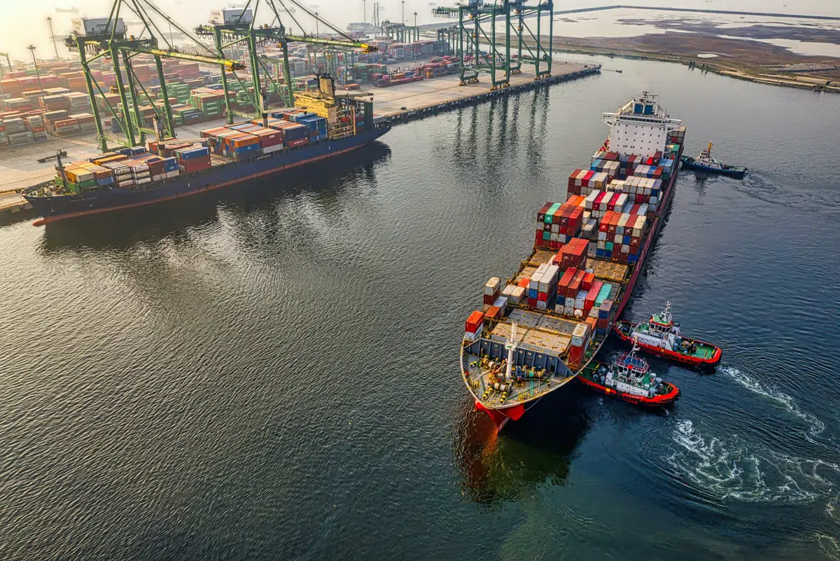 Container ship guided by tugboats into port